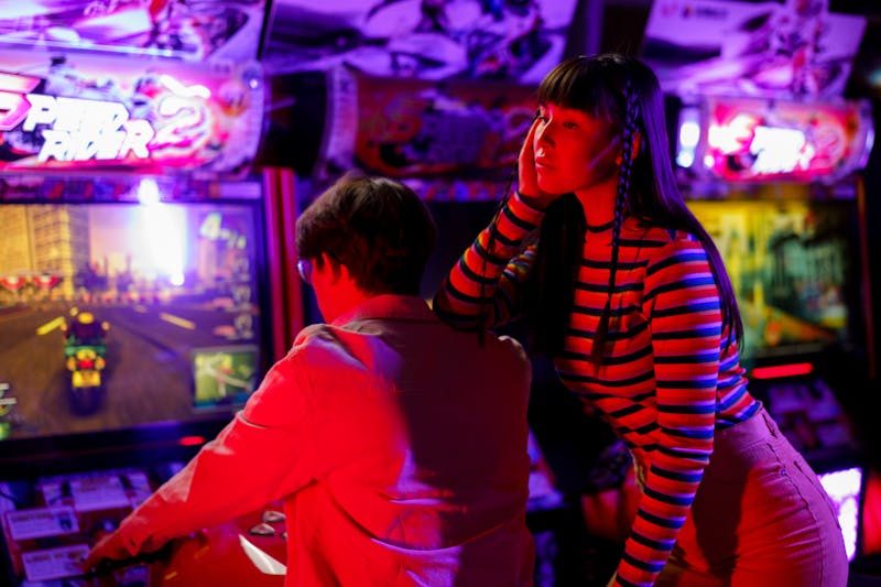 A dim arcade environment where faces are underlit and the scene is uniformly dark